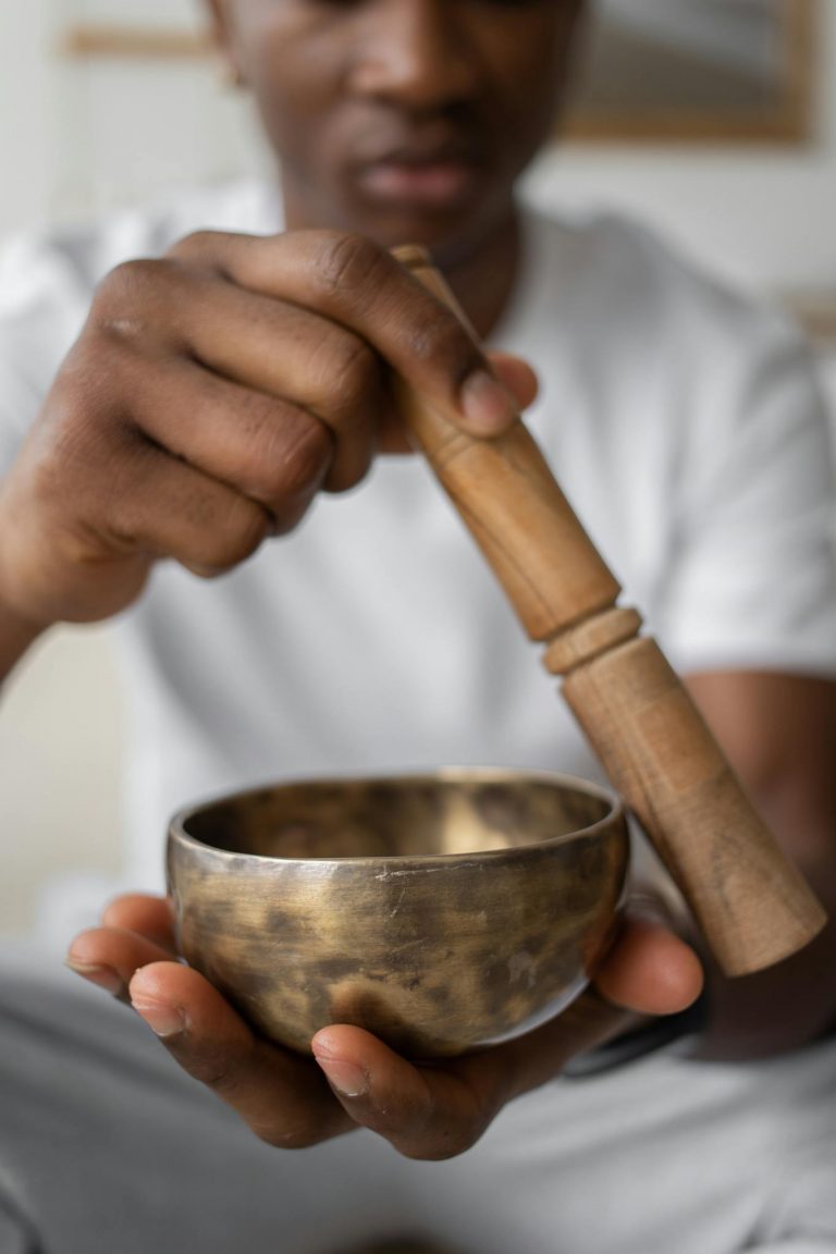 Close-up of a person using a singing bowl for meditation. Focus on hands and bowl.